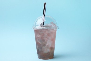 Photo of Tasty bubble tea in plastic cup on light blue background