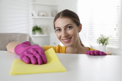 Young woman cleaning table with rag in office