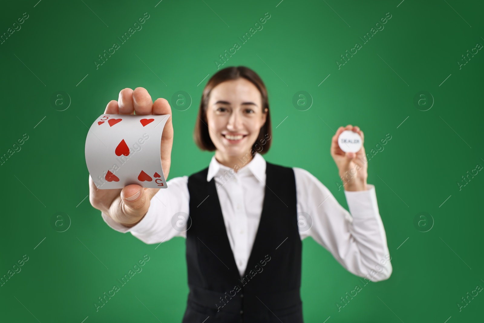 Photo of Croupier with cards and dealer button on green background