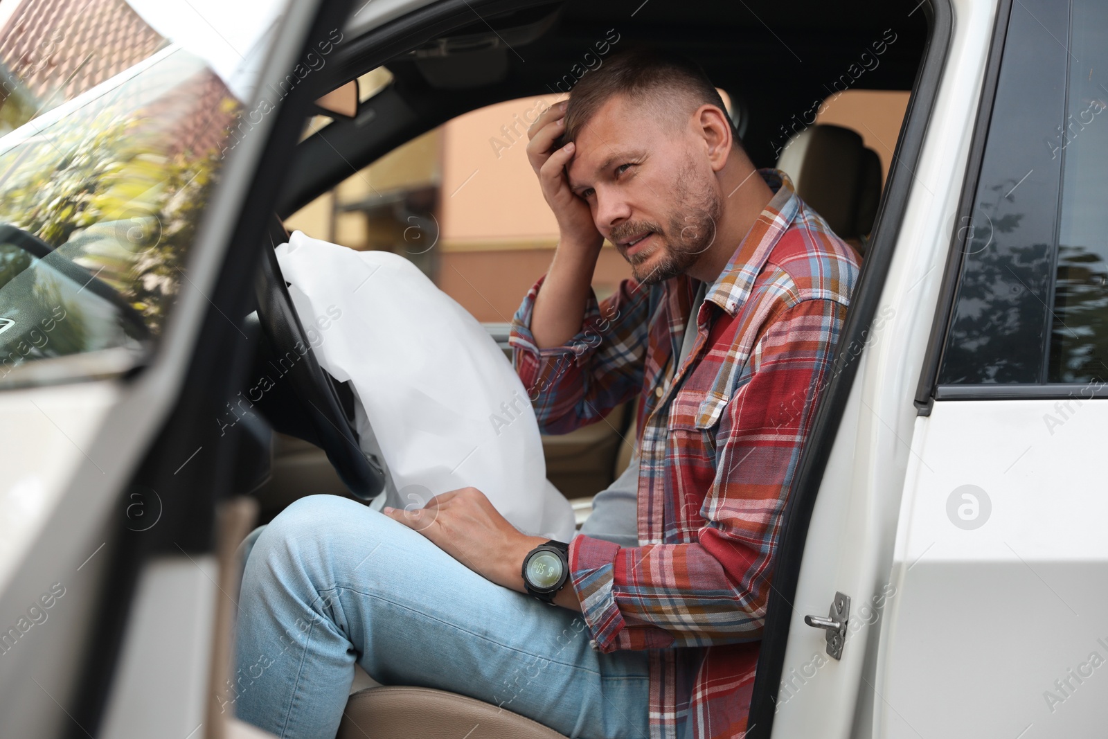 Photo of Injured man near opened airbag in automobile after car accident