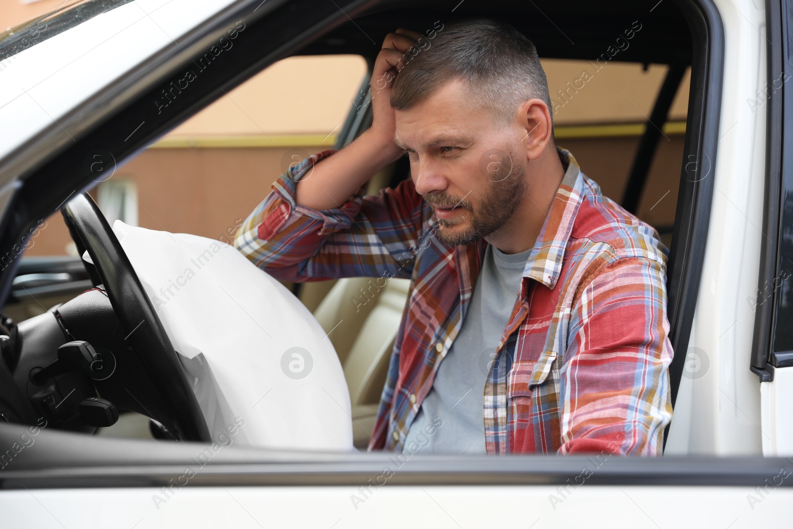 Photo of Injured man near opened airbag in automobile after car accident