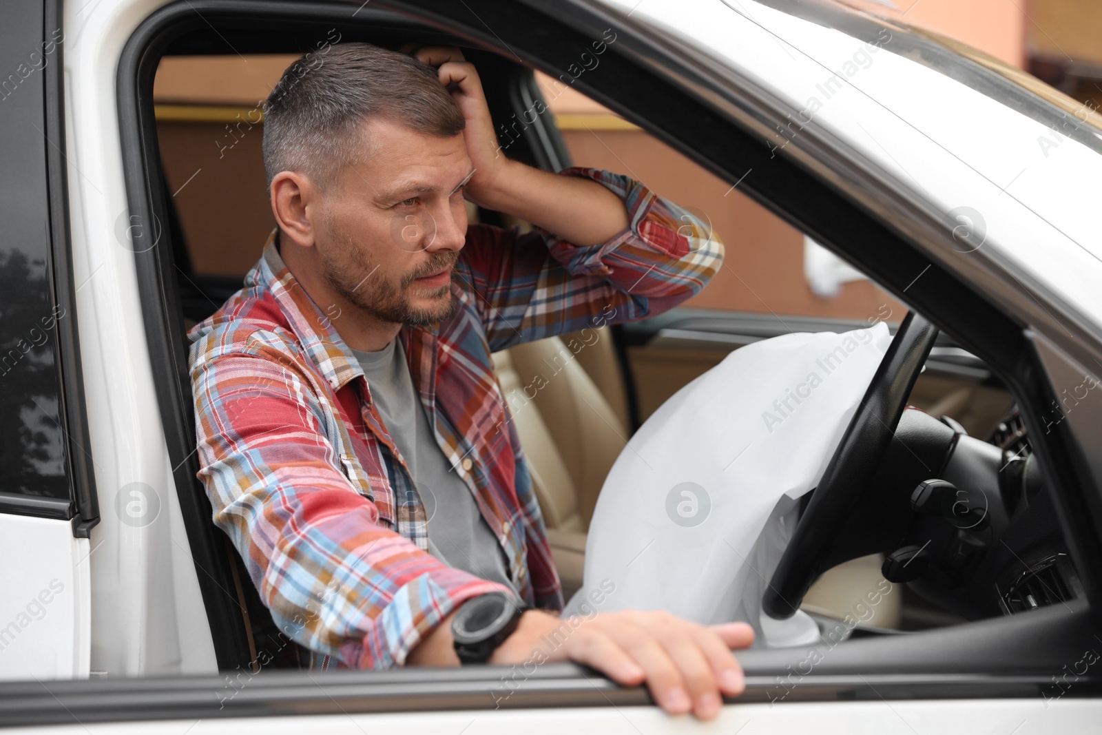 Photo of Injured man near opened airbag in automobile after car accident