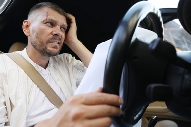 Photo of Injured man near opened airbag in automobile after car accident