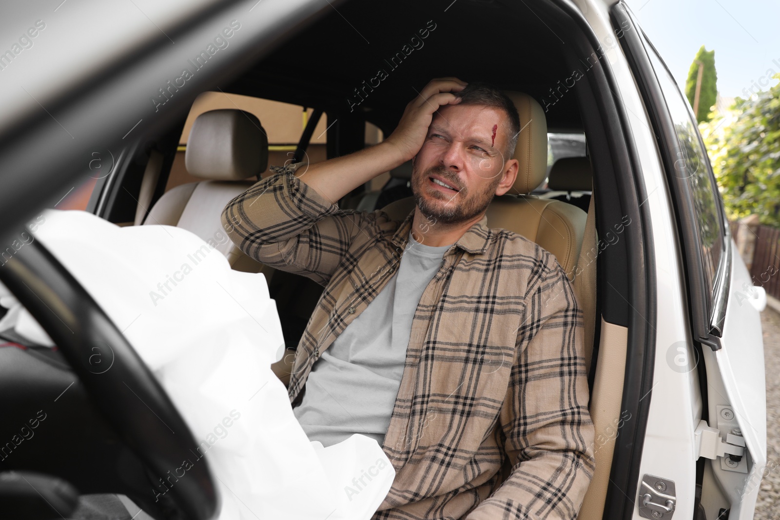 Photo of Injured man near opened airbag in automobile after car accident