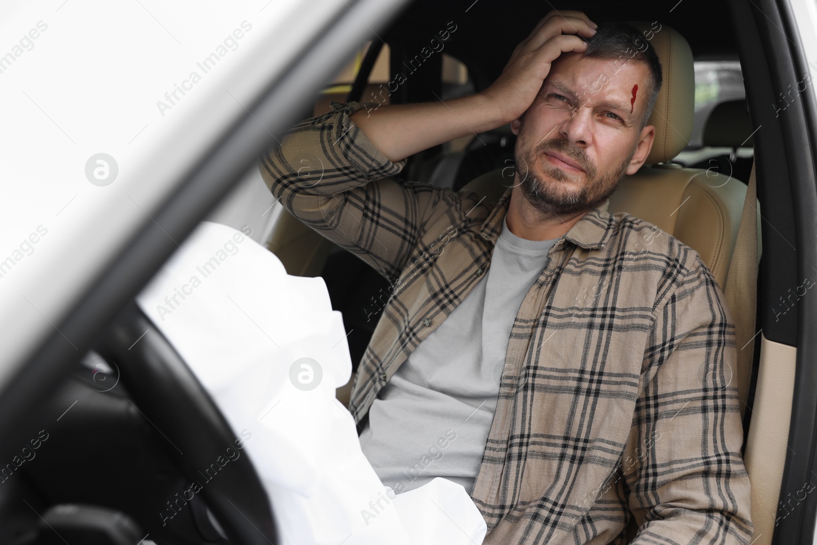 Photo of Injured man near opened airbag in automobile after car accident