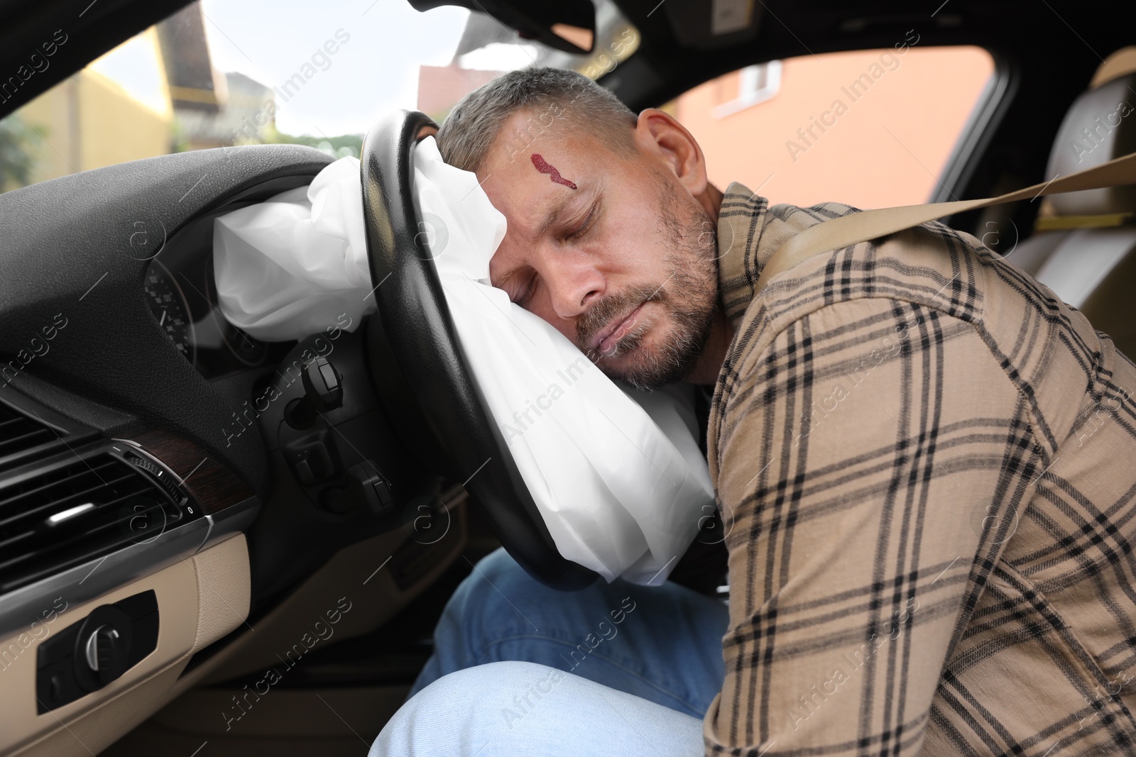 Photo of Unconscious man with head injury on airbag in automobile after car accident