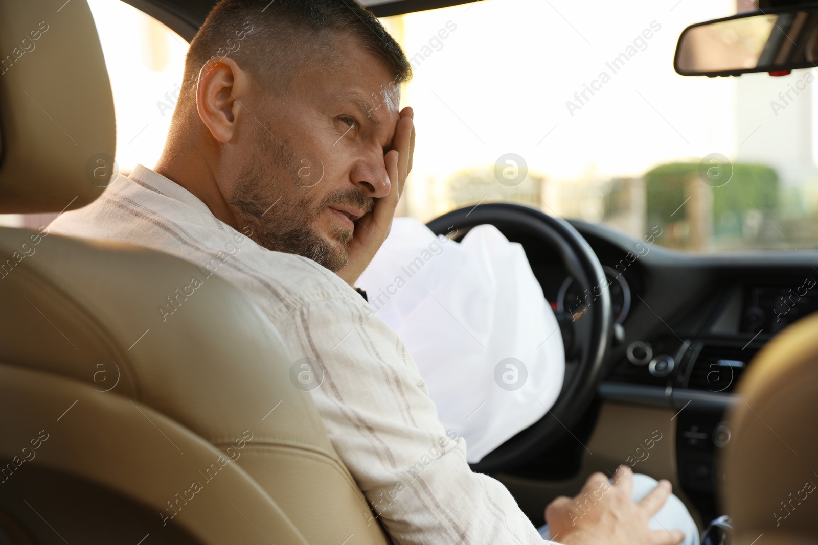 Photo of Injured man near opened airbag in automobile after car accident