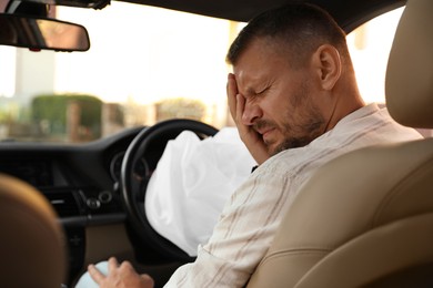 Photo of Injured man near opened airbag in automobile after car accident