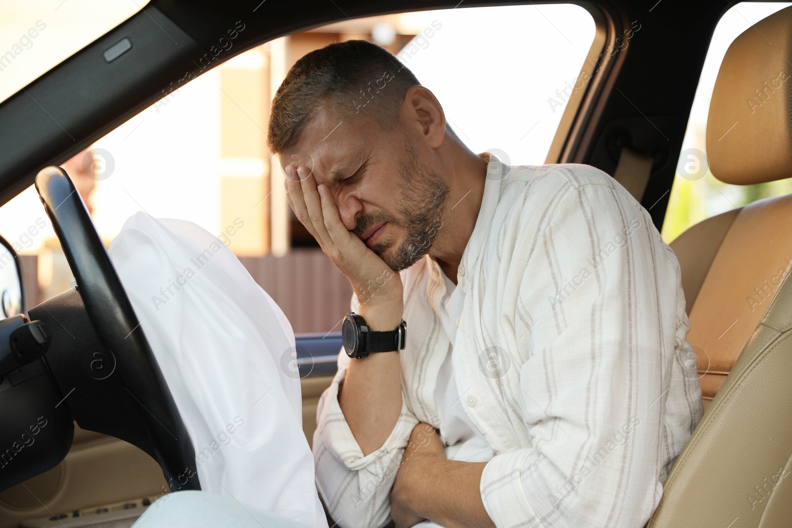 Photo of Injured man near opened airbag in automobile after car accident