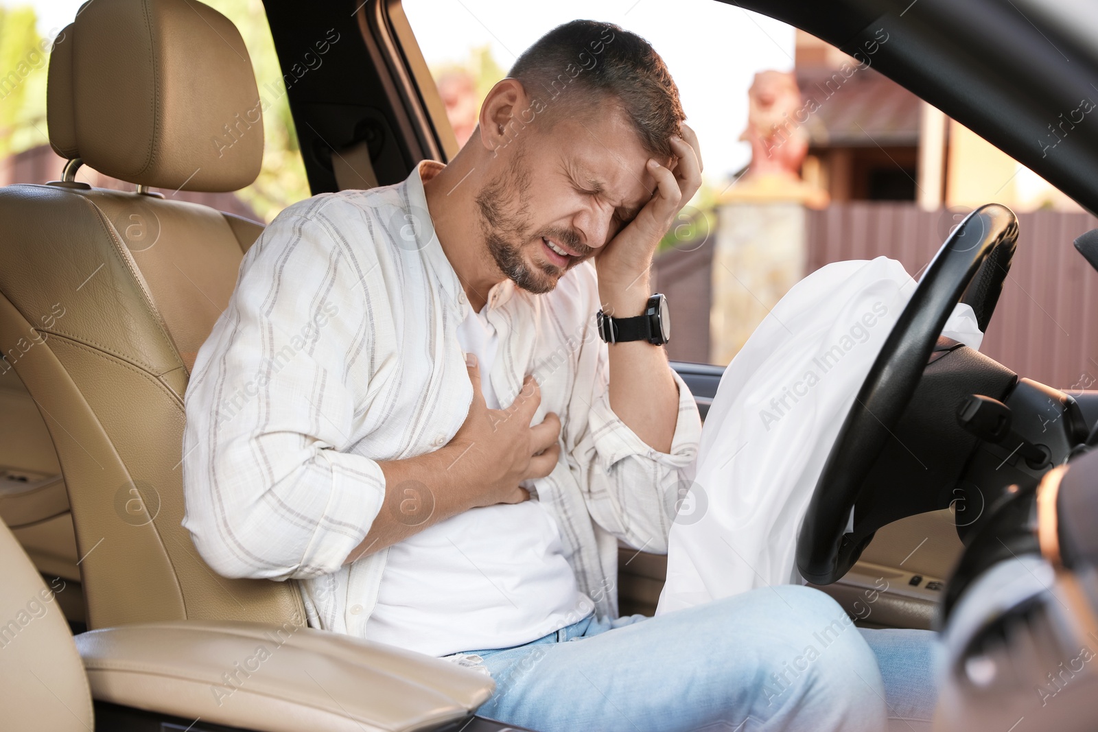 Photo of Injured man near opened airbag in automobile after car accident