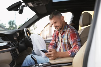 Man using smartphone near opened airbag in automobile after car accident