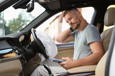 Photo of Injured man near opened airbag in automobile after car accident