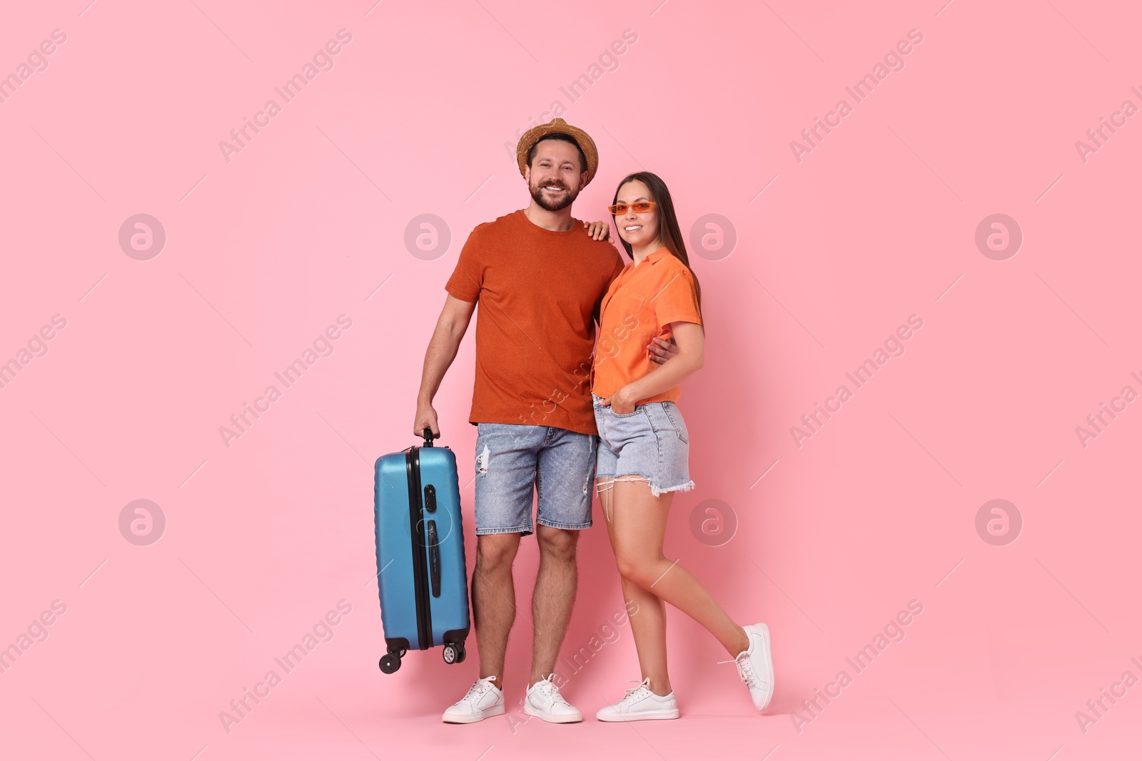 Photo of Happy woman and man with suitcase on pink background