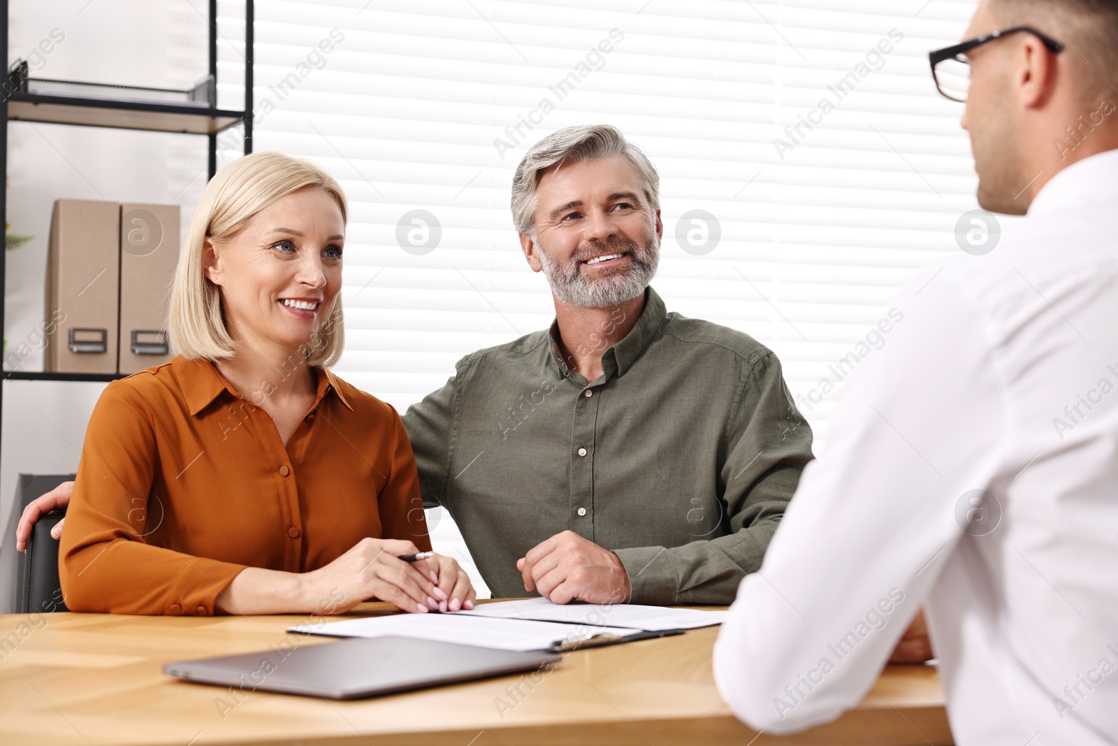 Photo of Pension plan. Couple consulting with insurance agent at table indoors