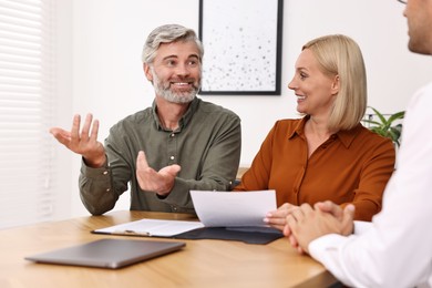 Pension plan. Couple consulting with insurance agent at table indoors