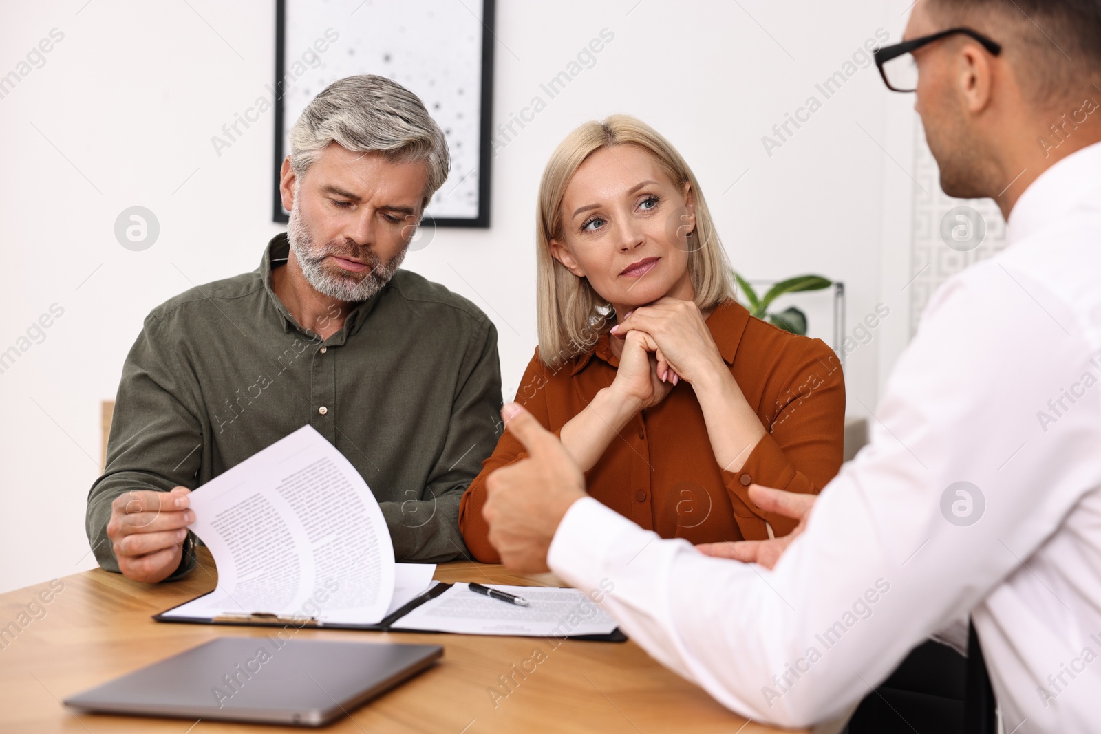 Photo of Pension plan. Couple consulting with insurance agent at table indoors