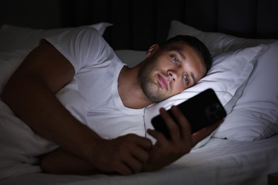 Bad habit. Man using smartphone in bed at night