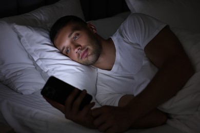 Bad habit. Man using smartphone in bed at night