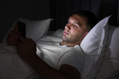 Bad habit. Man using smartphone in bed at night