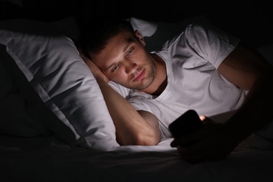 Bad habit. Man using smartphone in bed at night