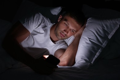 Bad habit. Man using smartphone in bed at night