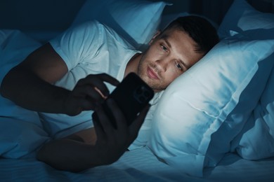 Bad habit. Man using smartphone in bed at night