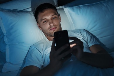 Bad habit. Man using smartphone in bed at night