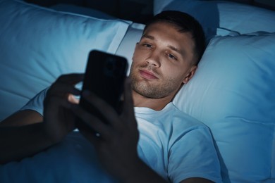 Bad habit. Man using smartphone in bed at night