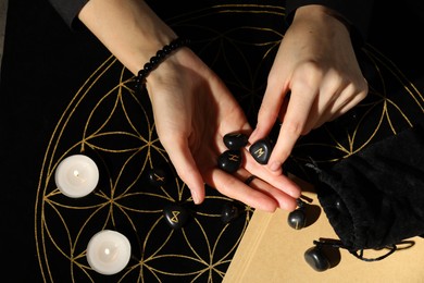 Photo of Woman with black runes at divination mat, top view