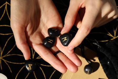 Photo of Woman with black runes at divination mat, top view