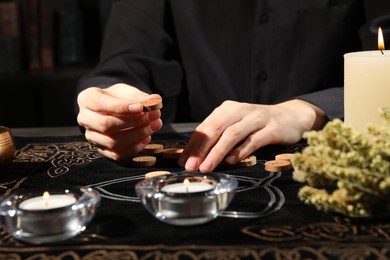 Photo of Woman with wooden runes at divination mat, closeup