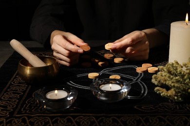 Photo of Woman with wooden runes at divination mat, closeup