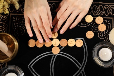 Woman with wooden runes at divination mat, top view