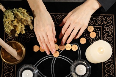 Photo of Woman with wooden runes at divination mat, top view