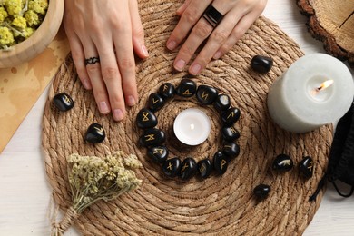 Woman with black runes at table, top view