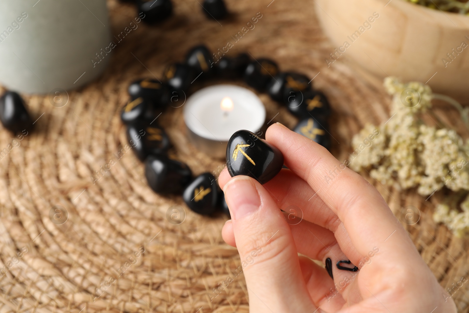 Photo of Woman with black rune Teiwaz at table, closeup