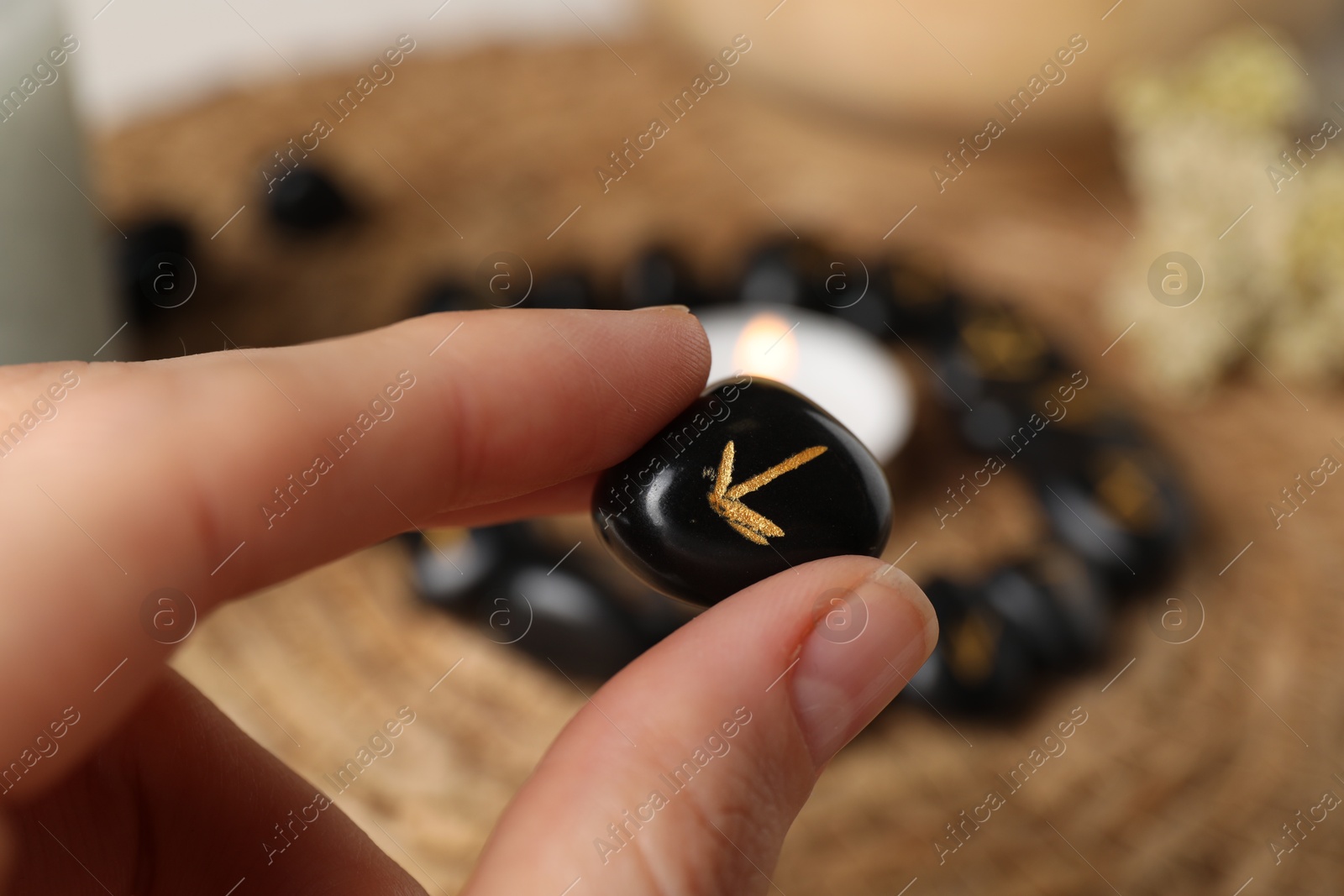 Photo of Woman with black rune Teiwaz at table, closeup