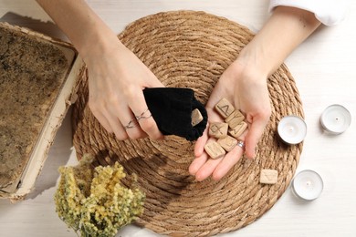 Photo of Woman with wooden runes at table, top view