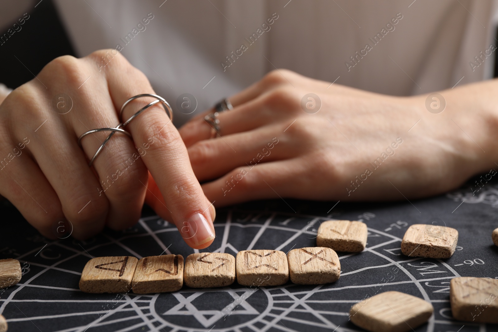 Photo of Woman with wooden runes at divination mat, closeup