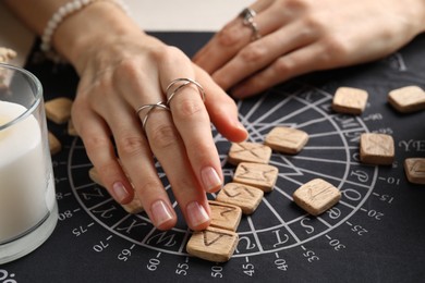 Photo of Woman with wooden runes at table, closeup