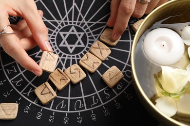 Photo of Woman with wooden runes at divination mat, top view