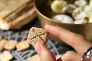 Woman with wooden rune Gebo at table, closeup