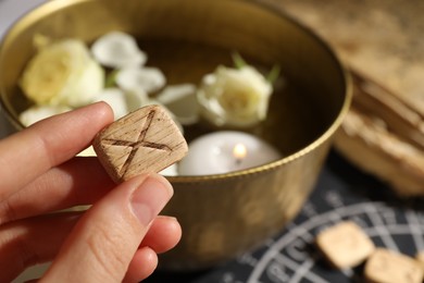 Photo of Woman with wooden rune Gebo at table, closeup