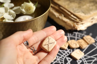 Photo of Woman with wooden rune Gebo at table, closeup