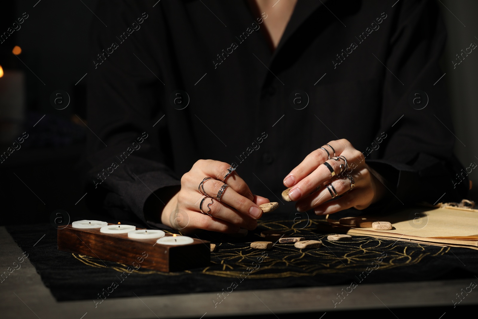 Photo of Woman with wooden runes at dark gray table, closeup