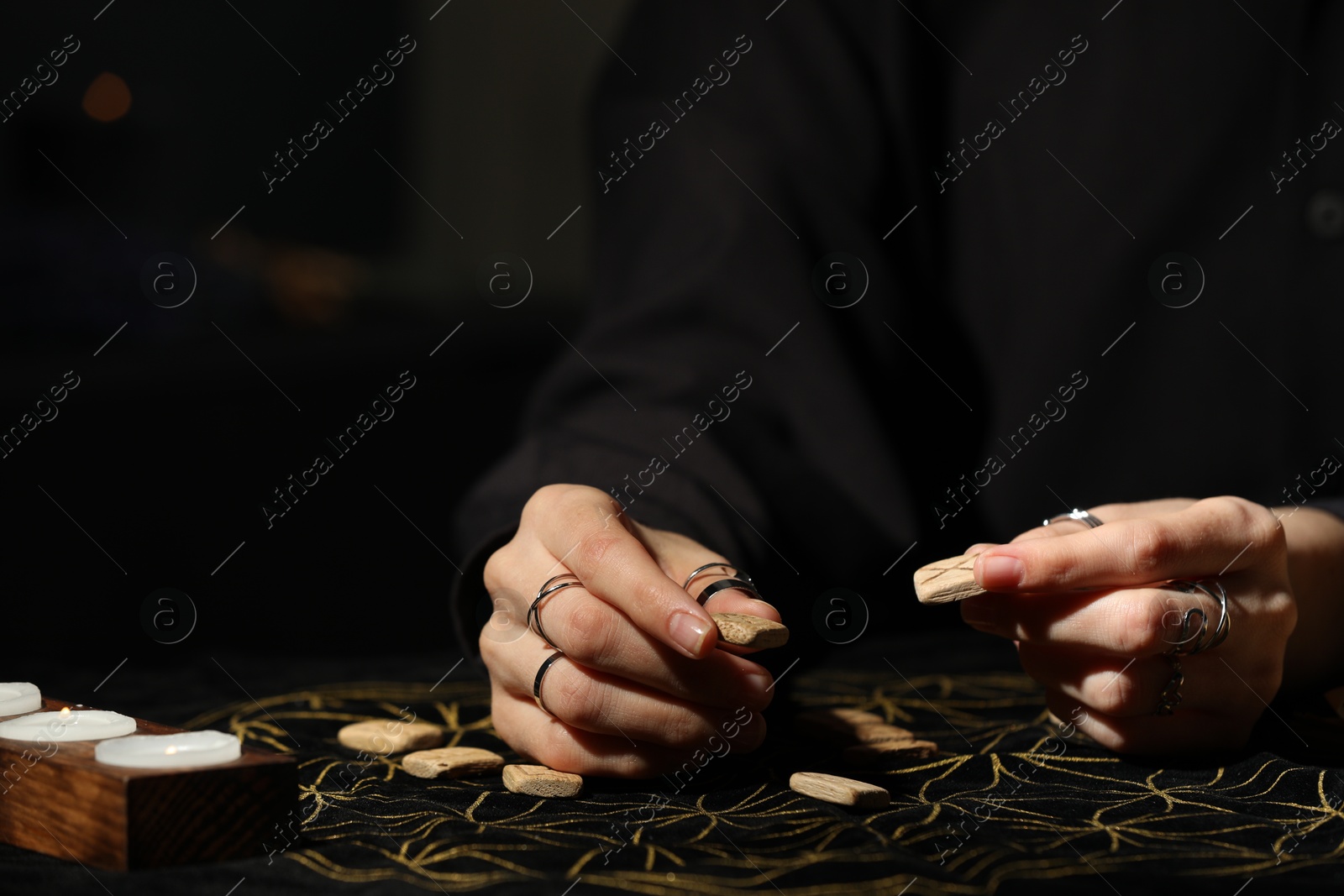 Photo of Woman with wooden runes at divination mat, closeup