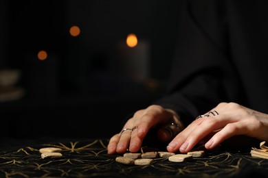 Photo of Woman with wooden runes at divination mat, closeup