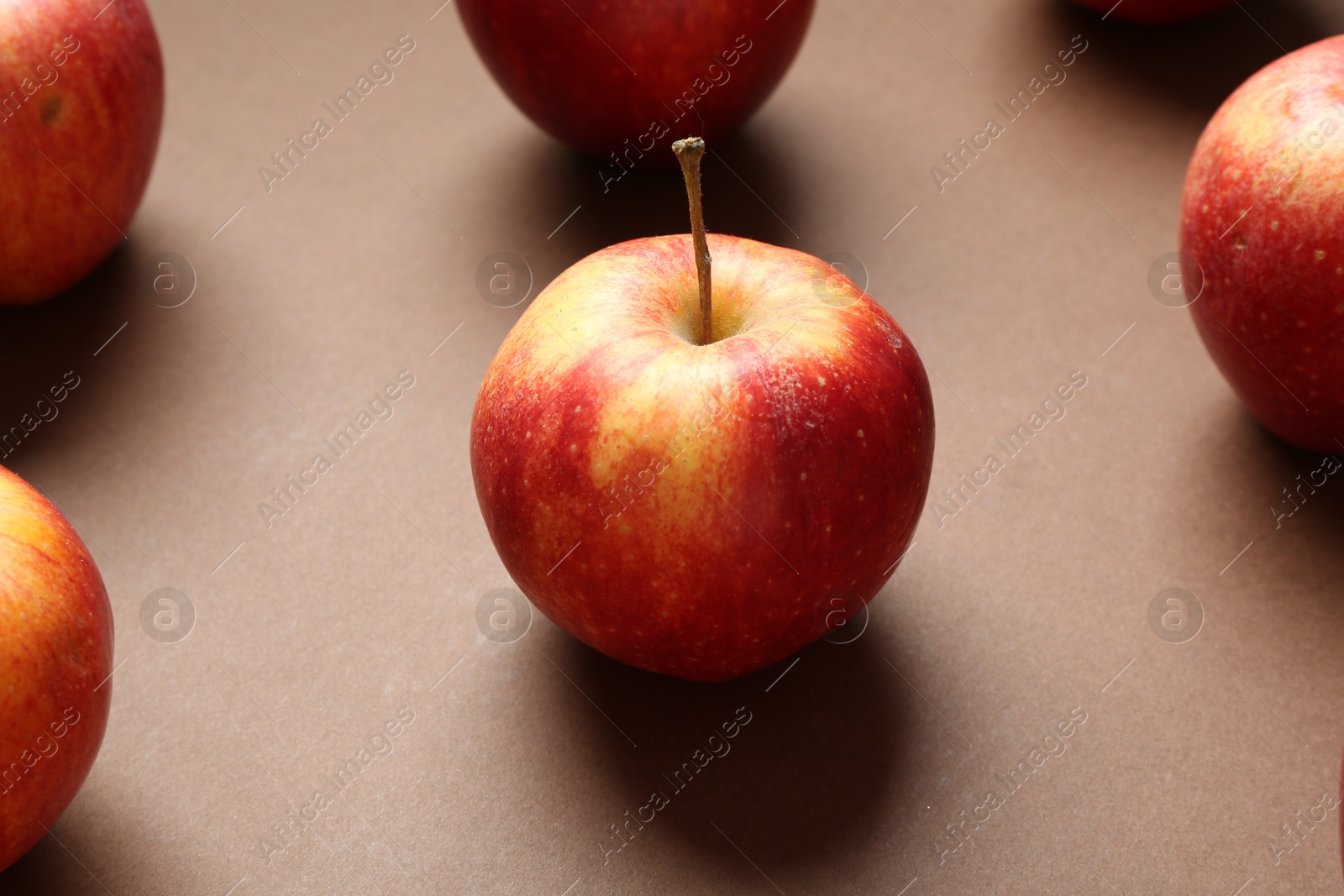 Photo of Ripe red apples on brown background, closeup