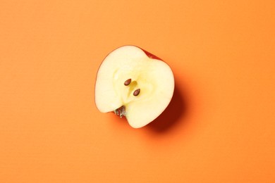 Photo of Cut fresh red apple on orange background, top view