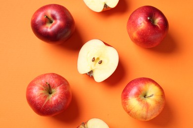 Photo of Whole and cut fresh red apples on orange background, flat lay